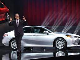 toyota ceo akio toyoda is on stage with an all new 2018 toyota camry sedan behind him nissan altima camry toyota camry