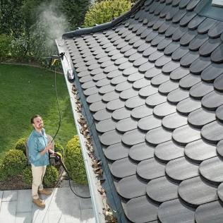 Clearing roof gutters prevents water from backing up under roof tiles, AI generated