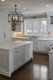 The dark blue counters in this kitchen break up the white of the cabinets and keep it from being overpowering. Farmhouse Lighting Wood Floor Kitchen Kitchen Remodel Kitchen Cabinets Decor