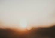 A blurry photo of the sun setting behind a building photo ...