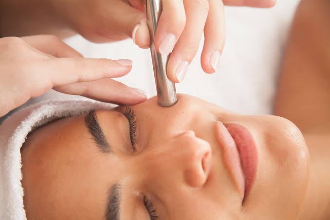 Cosmetologist using modern facial equipment