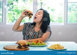 Mujer Gorda Asiática Sentada En La Mesa De Comedor Comiendo Una Hamburguesa  Foto de archivo 