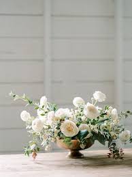 White Ranunculus Garden Rose And Snowberry Garden Style Centerpiece In A Low Flower Centerpieces Wedding White Floral Centerpieces Flower Arrangement Designs