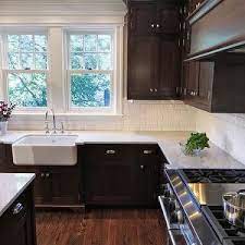The cabinets are made with a traditional farmhouse structure in mind, but their painted grey cabinets, white stone countertops, and subway tile backsplash keep the look fresh. Bradford Designs Kitchens Polished Carrara Marble Countertops Dark Walnut Cabine Trendy Kitchen Backsplash Espresso Kitchen Cabinets Dark Kitchen Cabinets