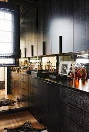 You can pair black cabinets with different countertops create a beautiful, modern color scheme by pairing your black cabinets and white counters with a gray waterfall island with a marble surface. Black Cabinets With Mirrored Backsplash Contemporary Kitchen