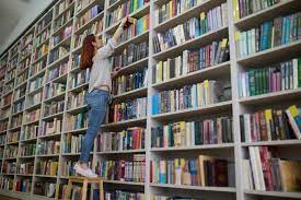 Bibliotecario Joven Busca Un Libro En Estanterías Foto de archivo - Imagen de lifestyle, alto: 261579388