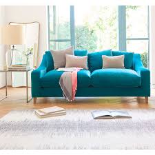 Open blue and white living room features a gray wood coffee table placed on a light gray rug beneath a truss ceiling. Velvet Sofas Our Pick Of Best Ideal Home