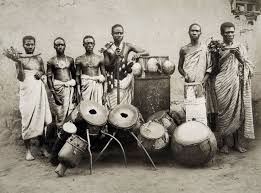 West Africans standing around cultural drums
