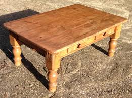 The tabletop is made from solid pine wood and has a butcher block style with visible wood grain and knots for a rustic, antique look. Old Pine Coffee Table With Drawers