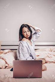 A Young Asian Webcam Model Girl Is Sitting In Front Of A Laptop. She  Communicates And Shows Her Charms. Low Depth Of Focus,artistic Photo  Processing Stock Photo, Picture and Royalty Free Image.