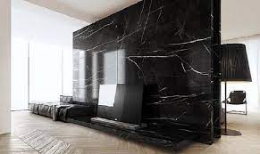 Elegant living room showcases a black textured wall fitted with a television and fireplace. Types Of Marble Comparison And Design Ideas Home Interior Design Black Marble Wall Interior Design