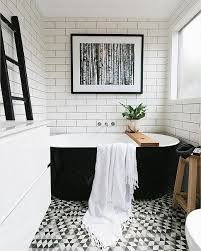 Traditional black and white bathroom with a double vanity, white beaded cabinets, black counter top, large tub, glass shower and built in shower shelves. 9 Gorgeously Graphic Bathrooms Courtesy Of Instagram Black White Bathrooms Free Standing Bath Tub Bathroom Inspiration