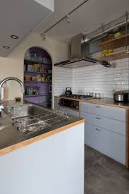 木の小口を見せてデザインのアクセントにしたキッチン アーチ型の開口の奥に覗く紫壁のパントリーも空間の彩りに house in chofu 紫の壁 パントリー キッチン