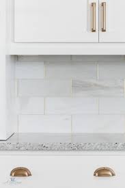 A Unique Backsplash Displays Honed White Tiles With Gold Trim Kitchen Marble Kitchen Tiles Backsplash Kitchen Renovation