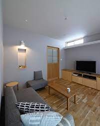 壁や天井はマットな質感のグレーの壁紙 ソファは濃い目のグレーの都会の小さな森の家のリビング 白マットのブラケットはグレーが背景になることで白の清潔感が引き立ちます リビングを落ち着く空間にするために明るい白い壁にせず敢えて少しトーンを落としたグレー