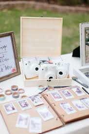 White Polaroid Cameras Sit On A Table Above A Sign In Book Where Guests Have Taped P Wedding Guest Book Table Wedding Guest Book Sign Wedding Guest Book Unique