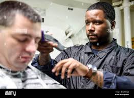 171001-N-RB168-288 WATERS NEAR GUAM (Oct. 1, 2017) Operations Specialist  1st Class Marcus Turner cuts Command Master Chief Matthew Lashley's hair  aboard the Arleigh Burke-class guided-missile destroyer USS Benfold (DDG  65). Turner used