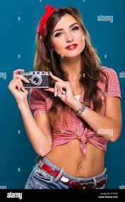 Pretty brunette girl, with piercing in the navel, wearing in checkered  shirt and red kerchief on her head, posing with retro cam Stock Photo -  Alamy