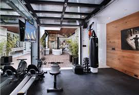 To cozy up the space, dark wood paneling and exposed brick were added to complement the garage's exposed ceiling beams. Home Gym Design Garage