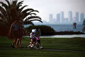 With the Tampa skyline in the background, US Air Force MASTER Sergeant Alex  Aceves and his wife, Starr, take a weekend stroll along MacDill's Bayshore  Boulevard with their children, Alex, 14 and