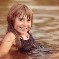 A little girl bending over in the water. Person human child.