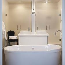 Modern bathroom design with back to back espresso stained single bathroom vanities, polished nickel gooseneck faucets, oval sinks, restoration hardware cade double sconces, faux wood tiles floor, stagger blue glass tiles back splash and white rolling bathroom cabinet. Double Sided Bathroom Vanity Design Ideas