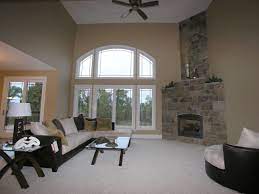 Living Room With High Ceilings Large Windows And Corner Fireplace Fireplace Corner Stone Fireplace Living Room With Fireplace