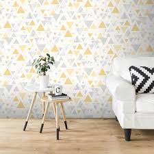 Photo armchairs and table in grey and yellow living room interior with posters above sofa. Debona Chantilly Triangle Geo Yellow Grey Metallic Wallpaper 5014