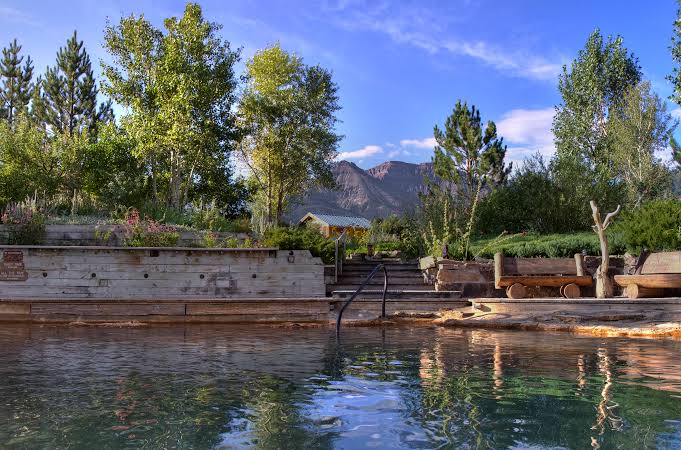 Steam rising from the gravel bottom soaking pond at Orvis Hot Springs in Ridgway Colorado with Mount Sneffels in the background