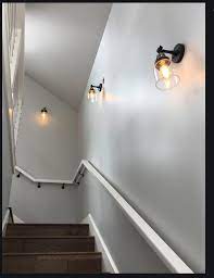 A pair of industrial sconces shine above the shelf and provide a glowing welcome for homeowners and houseguests, alike. Basement Stair Lighting Staircase Lighting Ideas Staircase Wall Lighting Stairway Lighting