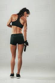Woman working out her back muscles and arms with pulley at the gym. Back View Of Pretty Muscular Woman In Grey Room With Exercise Bands Across Her Shoulders Stock Photo Dissolve