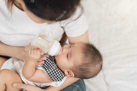 Premium Photo Mother Feeding Milk From Bottle And Baby Sleeping On A Bed