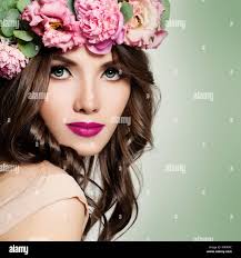 Schöne Mädchen mit Blumen Kranz. Lange Dauerwelle Curly Hair und Make-up.  Blossom Porträt der hübsche junge Frau mit rosa Blüten Stockfotografie