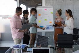 Business Colleagues Discussing About The Strategy On The Flip Chart Board In Modern Office