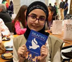 Hawraa-Jouni-of-Dearborn-Heights-shows-her-copy-of-Reuniting-the-Children-of-Abraham-at-the-DIA-event 