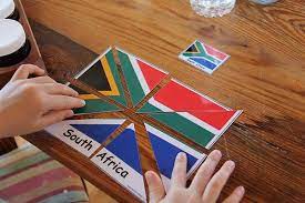 Pour a light amount of puzzle glue across the short end of the puzzle covering about a 6 inches section, working towards the opposite end. Chasing Cheerios South African Flag Puzzle South African Flag Montessori Geography Montessori Activities