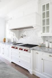 Stunning White Cooktop Designed With A White Wood Panel Range Hood Marble Subway Tiles And A Wolf Inte White Wood Kitchens White Wood Paneling Kitchen Cooktop
