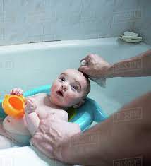 Father S Hands Bathing Baby Son In Baby Bath Stock Photo Dissolve