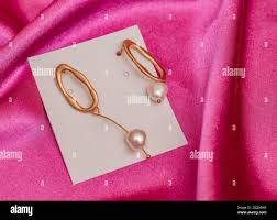 Modern Asymmetrical Golden Earrings With Pearl Beads On Pink Silk Background Stock Photo Alamy