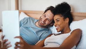 Happy, relax and carefree interracial couple on digital tablet smiling and  taking a selfie in bed.