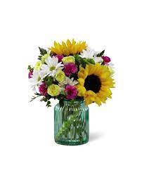 Gorgeous Sunflowers Are The Standout Bloom In This Arrangement Offset By Yellow Spray Roses Magenta Mini Carnations Flower Delivery Summer Flower Arrangements