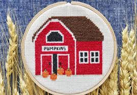 Cardinal barn quilt, shades of red, perched on tree leaves. Hygge Inspired Cross Stitch Patterns