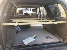It is a three part assembly with a cabinet door, slide out table, under storage and a sleeping area. A Storage Shelf Built Into A 1998 Toyota 4runner Suv Rving
