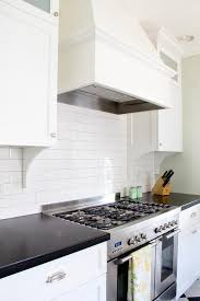 The backsplash is taken to just below the wood. White Wood Kitchen Hood With All White Subway Tiles Transitional Kitchen