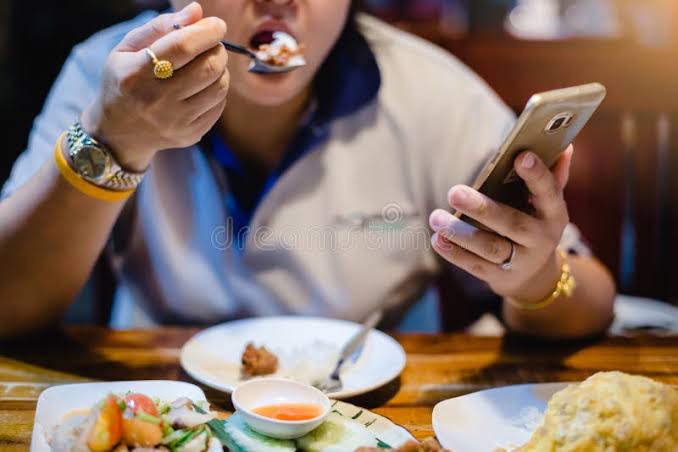 Woman is Eating Along with Playing Smartphone. Lifestyle in Today`s Society Stock Photo - Image of looking, breakfast: 151935836