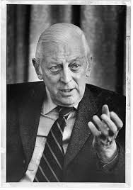 Alistair Cooke, head-and-shoulders portrait, facing front, gesturing with  left hand, during interview]