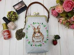 dear blue bunny 手作工房剌繡小兔花環星星口金包手工製作 接單訂製 付款後 從開始製作到寄出商品為3 個工作天 不包含假日 選用淺灰色細麻布機繡可愛小兔和花環點綴玻璃角珠每顆玻璃角珠皆以手縫固定尺寸 寬11cm 高19 5cm 底5cm附