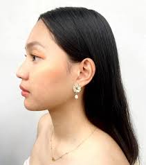 TAHITI • a delicate bloom of pastel florals crowned with a luminous pearl  drop Materials: stainless steel, gold plated, freshwater pearl,  rhinestones, resin Size: 2×3cm In Frame: Giessell