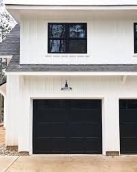 Black And White House With Wood Garage Door Modern Farmhouse With White Clapboard Siding Black Garage Doors And Windows And Deep Overhangs Garage Doors Garage Door Design Black Garage Doors