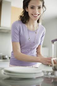 4,887 woman washing dishes premium high res photos. Woman Washing Dishes In Kitchen And Looking At Camera Front View Lifestyle Stock Photo 222925008